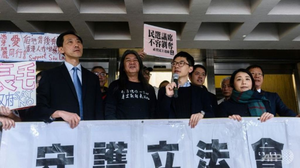 Elected pro-democracy lawmakers (L-R) Edward Yiu, “Long Hair” Leung Kwok-hung, Nathan Law and Lau Siu-lai hold a banner outside the High Court in Hong Kong AFP/Anthony WALLACE.