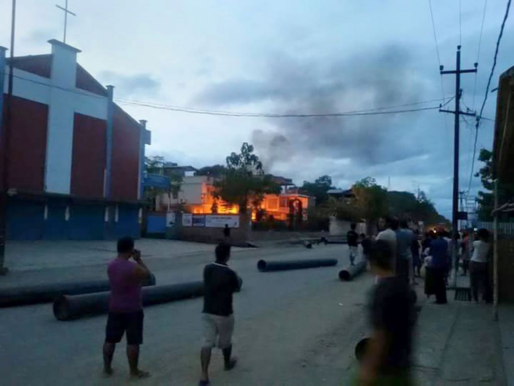 (FILES) This file photo taken on August 31, 2015 shows Indian people watching a blaze at the residence of Manipur state health minister Phungzaphang Tonsimg that was torched during a protest against controversial tribal rights laws, at Churachandpur, some
