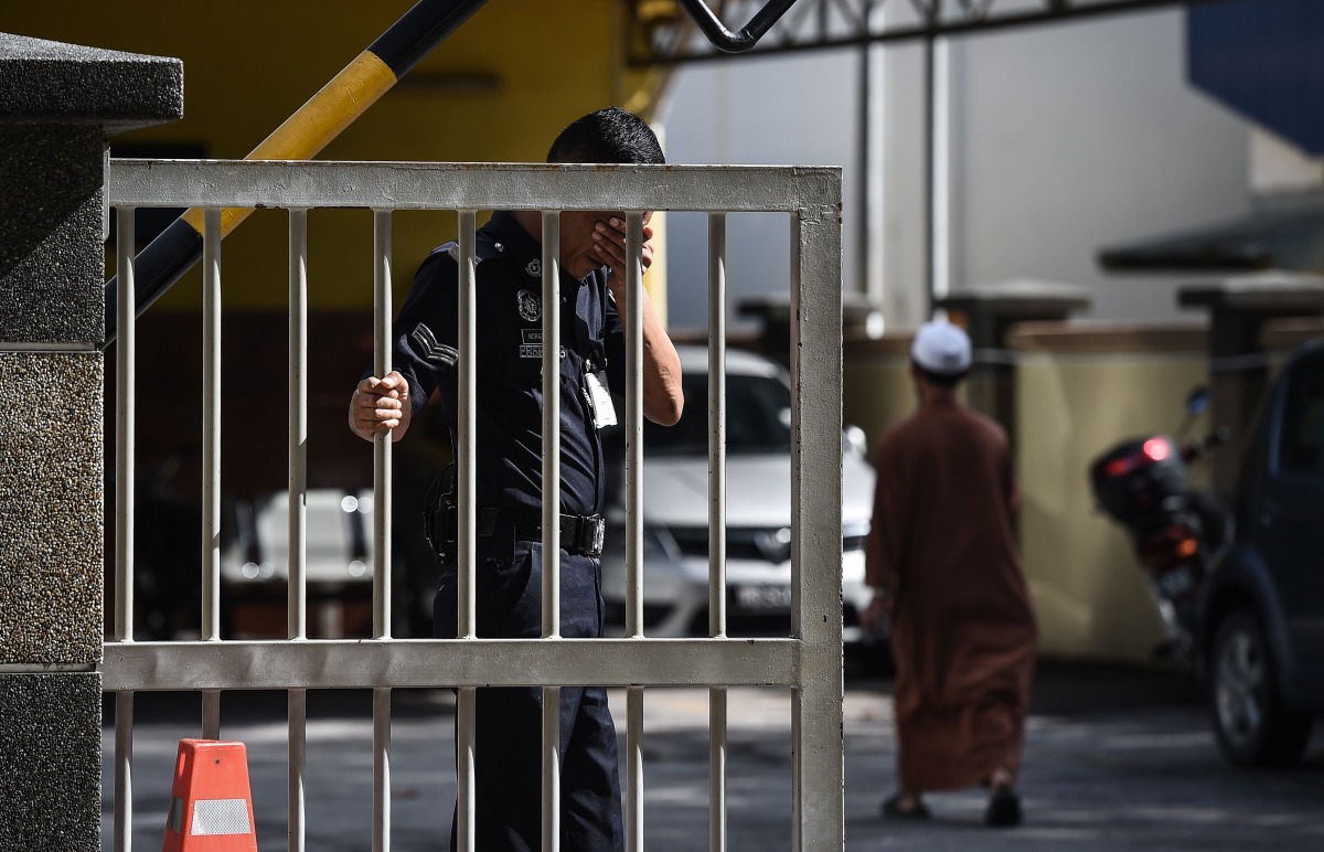 A Malaysian policeman wipes his face as he holds the gate of the forensics wing of the Hospital Kuala Lumpur where the body of Kim Jong-Nam, the half-brother of North Korean leader Kim Jong-Un, is being kept in the Malaysian capital on March 4, 2017. / AF