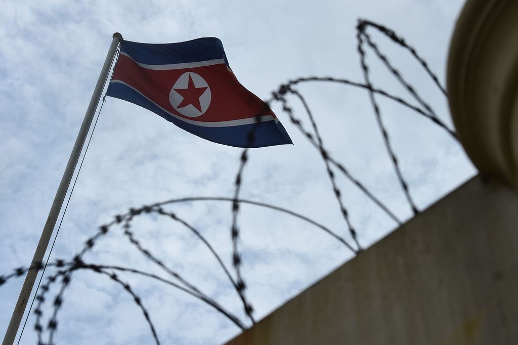 The North Korean flag is seen past a barbed-wire fenced wall of the North Korean embassy in Kuala Lumpur on March 5, 2017. AFP / Lillian Suwanrumpha 