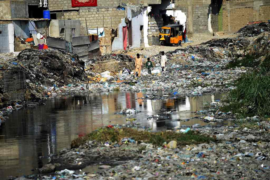 In this photograph taken on January 24, 2017, Pakistani youths search for their ball as they walk amongst dumped garbage at a residential area of Karachi. AFP / Rizwan Tabassum 