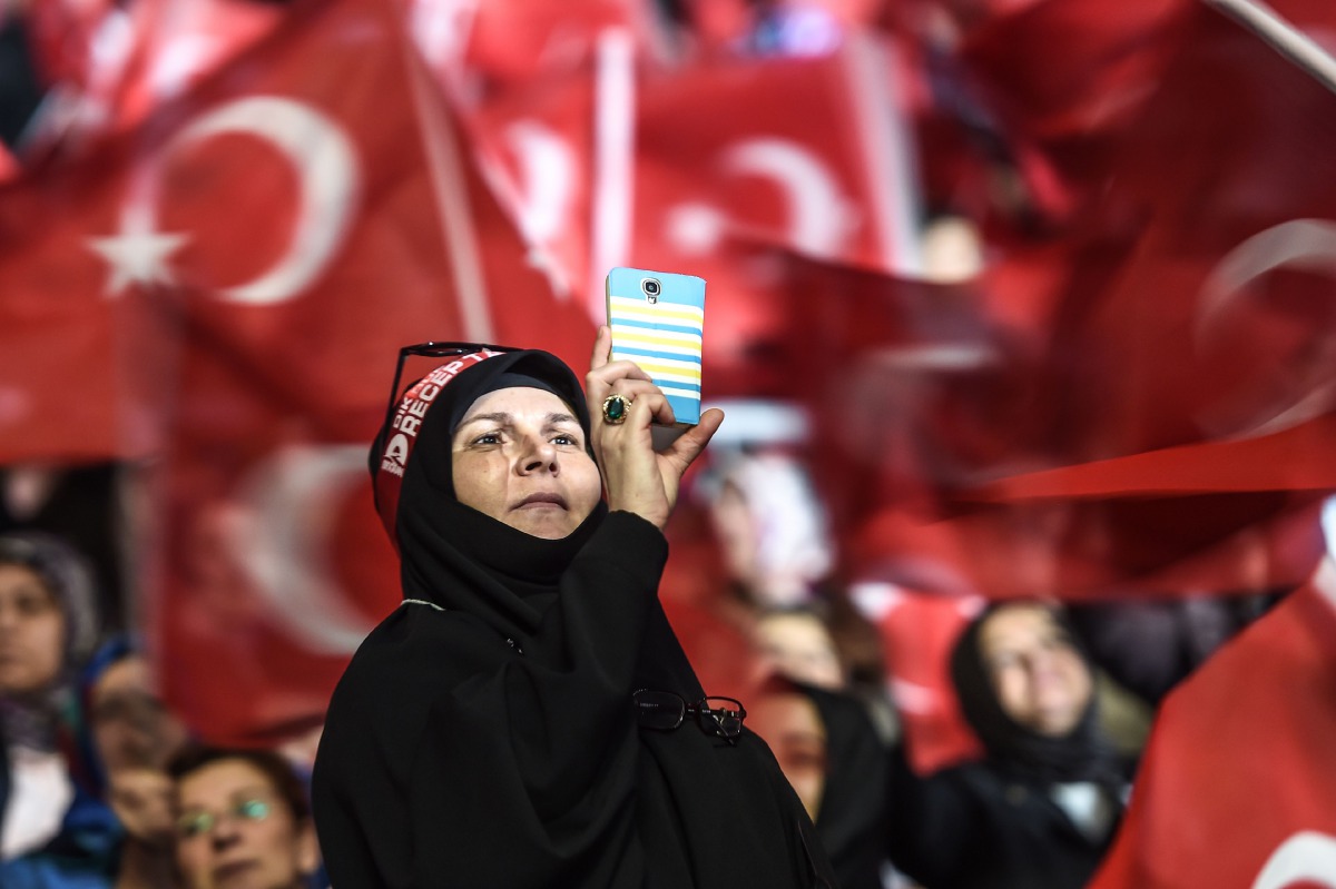 Women wave Turkish national flags as a woman takes pictures on March 5, 2017 in Istanbul during a pro-government women meeting. Some 12,000 women filled on March 5 an Istanbul arena in support of a 