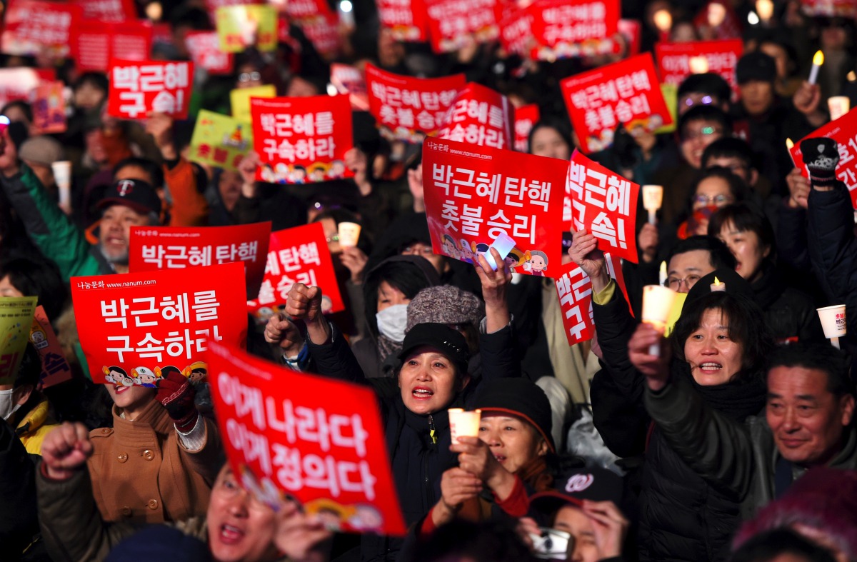 South Korean demonstrators hold up red banners reading 