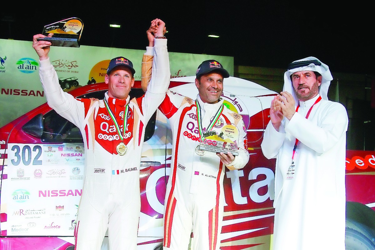 Qatar's Nasser Saleh Al Attiyah (centre) and his French navigator Matthieu Baumel, winners of the inaugural Dubai International Baja, pose for a photograph with Mohammed Ben Sulayem, President Emirates Motorsport Federation (right) during the presentation