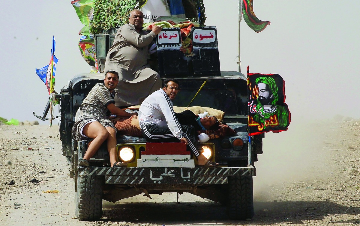 Iraqi federal police transport civilians, injured while opening a booby-trapped shop in Tayaran district of west Mosul, yesterday.