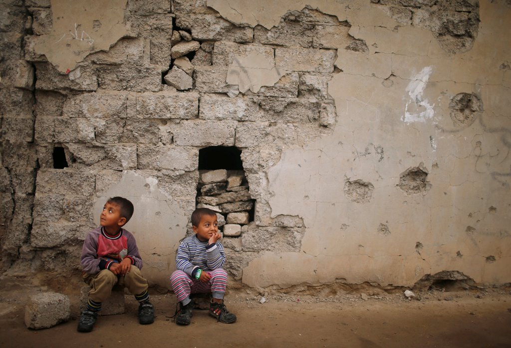 Iraqi boys sit outside their house that was damaged during the fighting between Iraqi forces and Islamic State militants, south of Mosul, Iraq March 15, 2017. REUTERS/Suhaib Salem
