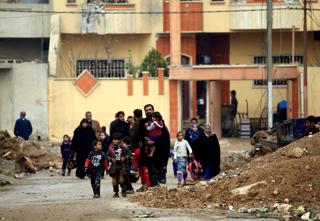 Displaced Iraqi families who fled from clashes during a battle between Iraqi forces and Islamic State militants, walk with their children in al-Sumood neighbourhood of Mosul, Iraq March 15, 2017. REUTERS/Thaier Al-Sudani

