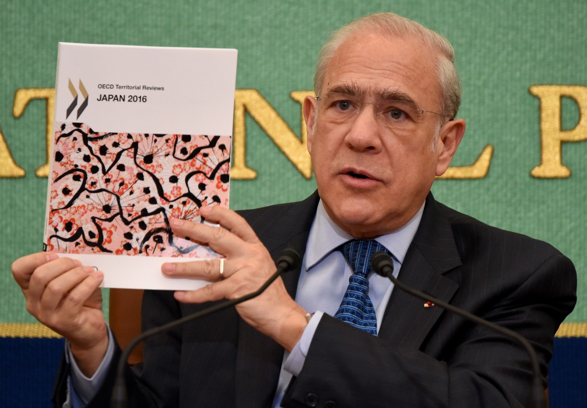 FILE PHOTO: OECD Secretary General Angel Gurria holds up a copy of the Japan 2016 OECD Territorial Review during a press conference in Tokyo on April 11 2016 AFP TORU YAMANAKA