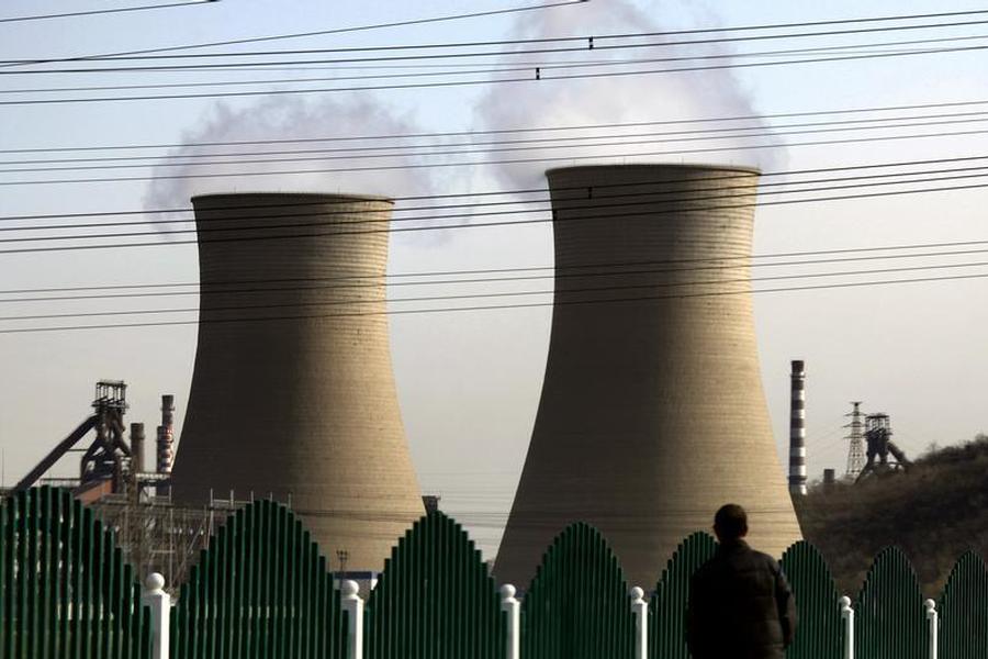 A man looks over a fence towards chimneys of a coal-burning power station located on the outskirts of Beijing, REUTERS/David Gray
