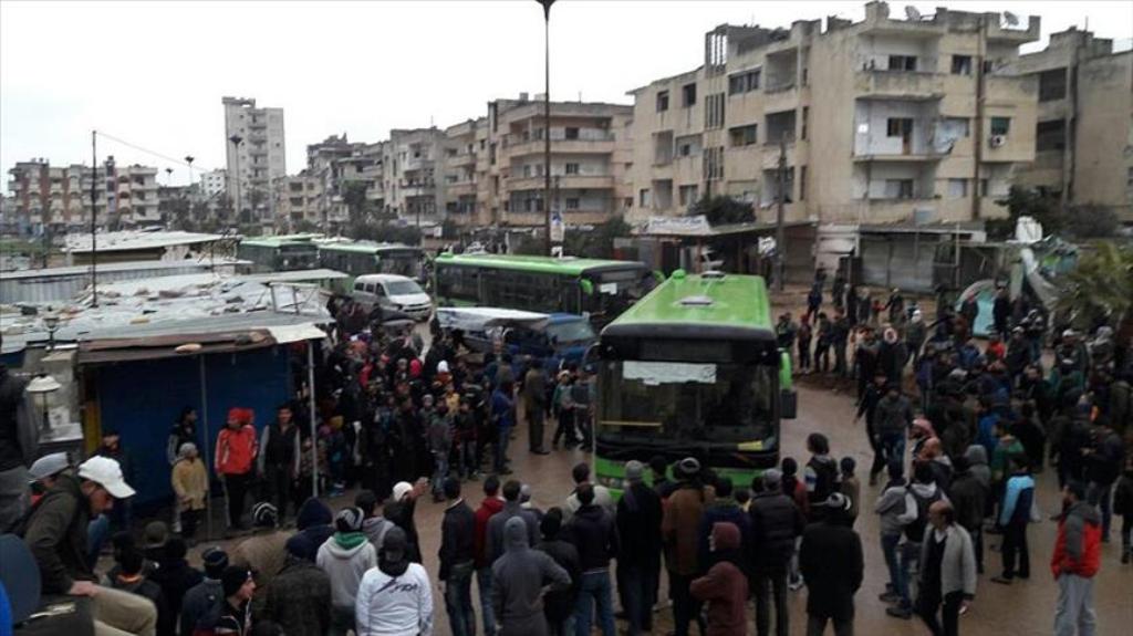 Syrian oppositions walk to get into a bus during an evacuation from the al-Waer neighborhood, in the western outskirts of the central city of Homs, Syria on March 18, 2017. ( Stringer - Anadolu Agency ).