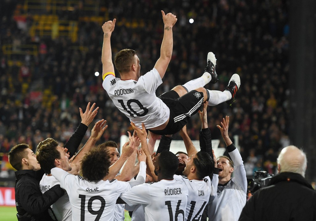 TOPSHOT - Teammates throw Germany's midfielder Lukas Podolski in the air after the friendly football match of Germany vs England in Dortmund, western Germany, on Marcht 22, 2017.   AFP / dpa / Bernd Thissen