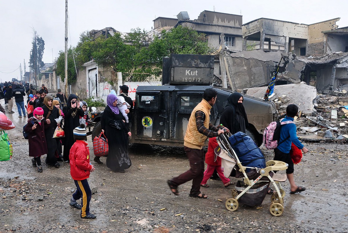 Iraqi civilians evacuate the area as the Iraqi counter-terrorism service (CTS) advance towards the Yabasat neighbourhood on March 23, 2017 during their ongoing offensive to push Islamic State (IS) jihadists out of Mosul. About 600,000 people remain in the