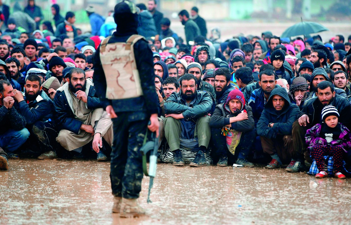 Civilians fleeing the city of Mosul sit under the rain yesterday as Iraqi forces advance in their massive operation to retake the second city from the Islamic State group. 