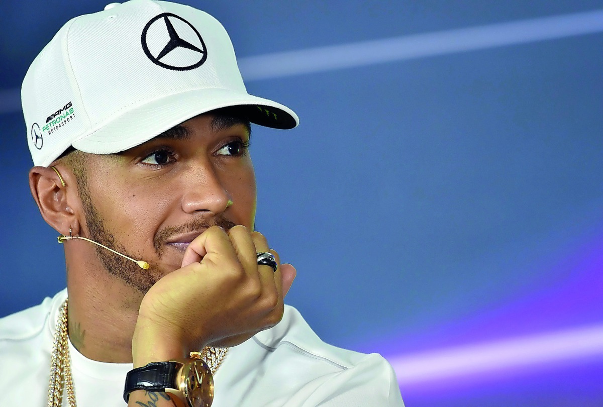 Mercedes' British driver Lewis Hamilton speaks during a press conference in Melbourne yesterday (left). Hamilton's helmet is also seen (inset).  