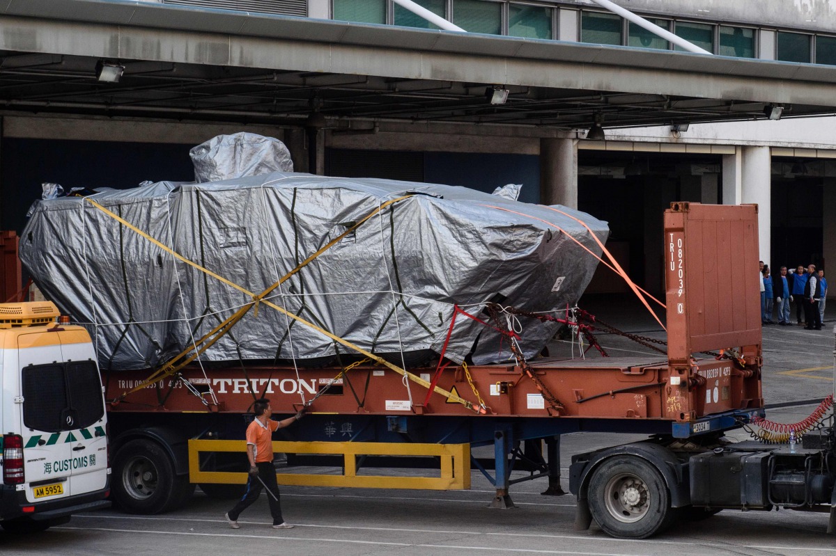 This file photo taken on January 26, 2017 shows a worker walking past an impounded tarpaulin-covered armoured troop carrier Terrex vehicle belonging to the Singapore military, after it was placed by crane onto a truck, at a customs and excise facility in 