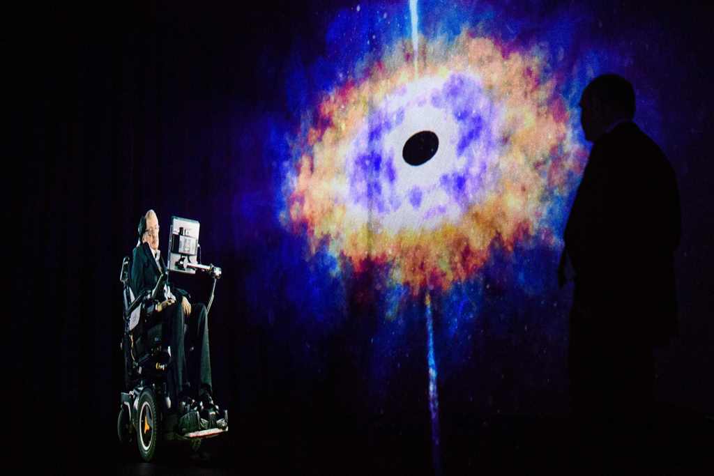 In this picture taken on March 24, 2017, renowned physicist Stephen Hawking, 75, speaks to an audience by hologram (L) in Hong Kong, beamed live from his office in Cambridge, England. AFP / Anthony WALLACE
