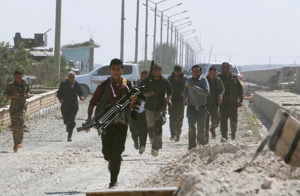 Engineers, journalists and Syrian Democratic Forces (SDF) fighters run for cover after Islamic State shelled positions held by the SDF at the Tabqa Dam on the Euphrates River, Syria March 29, 2017. REUTERS/Rodi Said 