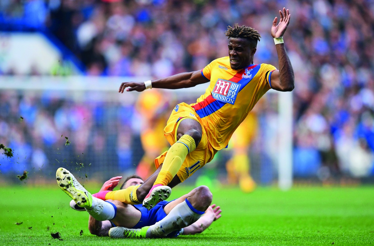 Crystal Palace's Ivorian-born English striker Wilfried Zaha (up) vies with Chelsea's English defender Gary Cahill during the English Premier League football match between Chelsea and Crystal Palace at Stamford Bridge in London on April 1, 2017. AFP / Glyn