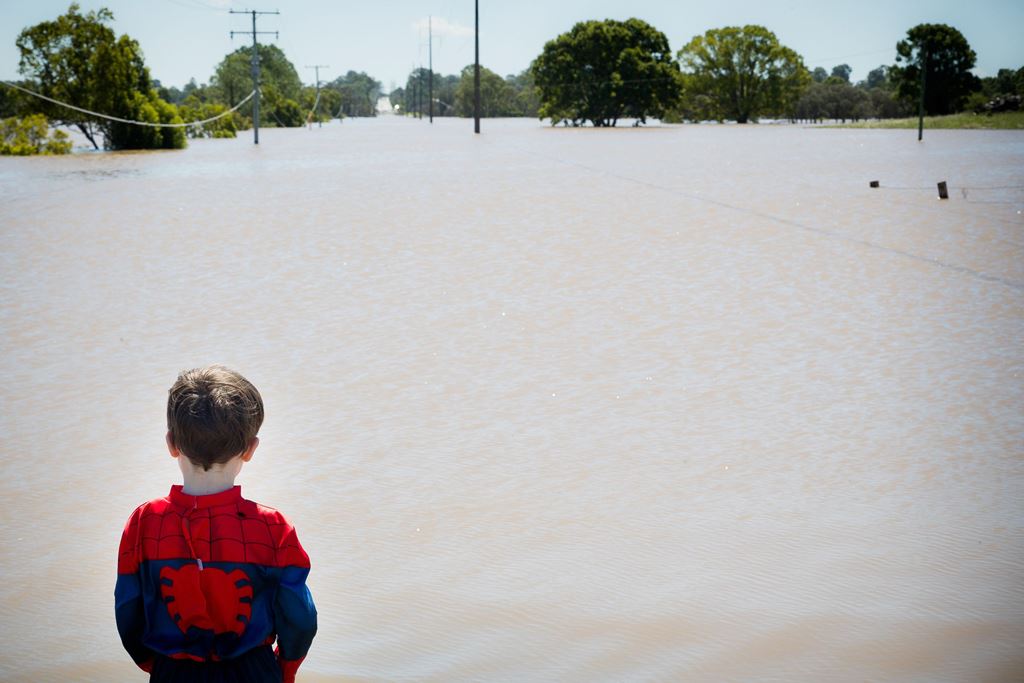 Seth Skirving, 5, watches floodwaters of the Logan River, caused by Cyclone Debbie, flow over the Mt Lindesay Highway in Waterford West near Brisbane on April 1, 2017. AFP / Patrick HAMILTON