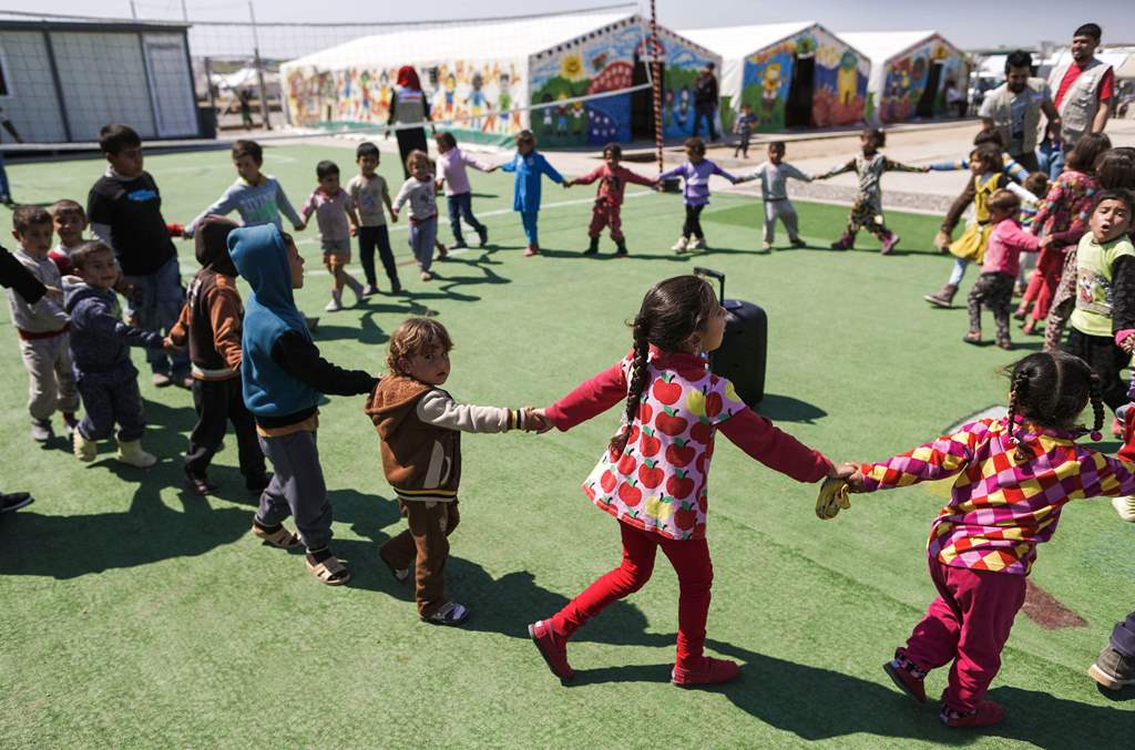 Displaced children who fled Mosul play outside of tents in a playground at Hasan Sham camp, 30 kilometres (20 miles) east of Mosul, on March 26, 2017. AFP / AHMAD GHARABLI
