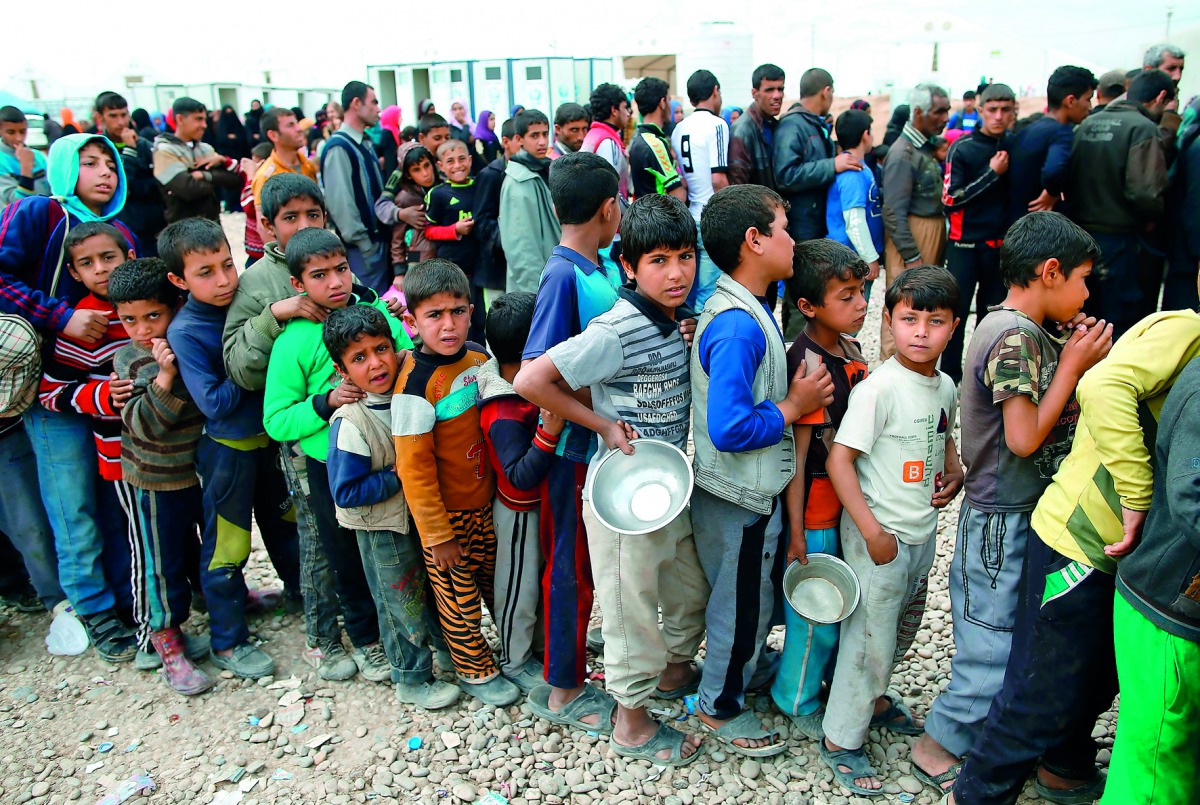 Displaced Iraqis, who fled Mosul due to the ongoing fighting between government forces and Islamic State (IS) militants, receive food at the Hammam Al Alil camp, south of Mosul, yesterday.