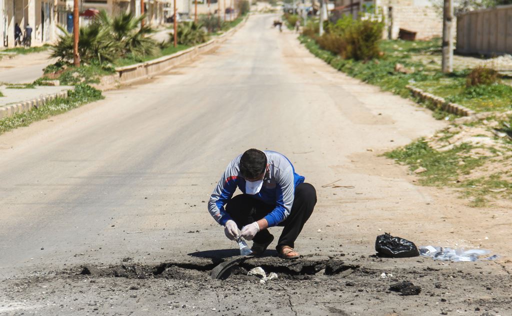 A Syrian man collects samples from the site of a suspected toxic gas attack in Khan Sheikhun, in Syria's northwestern Idlib province, on April 5, 2017. AFP / Omar haj kadour
