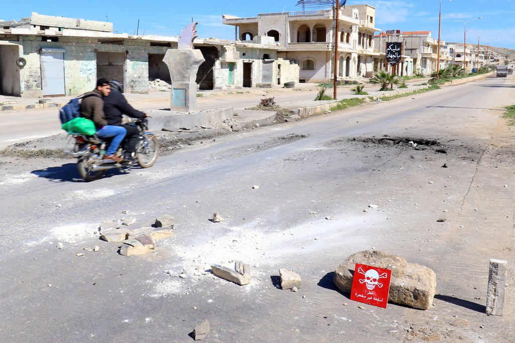 Men ride a motorbike past a hazard sign at a site hit by an airstrike on Tuesday in the town of Khan Sheikhoun in rebel-held Idlib, Syria April 5, 2017. The hazard sign reads, 