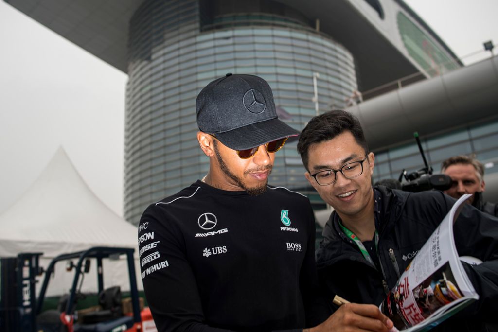Mercedes' British driver Lewis Hamilton signs an autograph for a Chinese fan in the paddock in Shanghai on April 6, 2017, ahead of the Formula One Chinese Grand Prix. / AFP / Johannes EISELE
