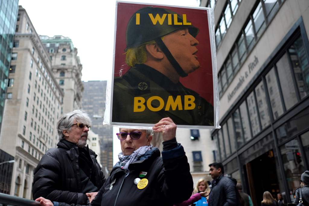 An anti-war protester displays a placard against US President Donald Trump during a demonstration in front of the Trump Tower in New York on April 7, 2017, to protest the US air strike in Syria.  AFP / Jewel SAMAD