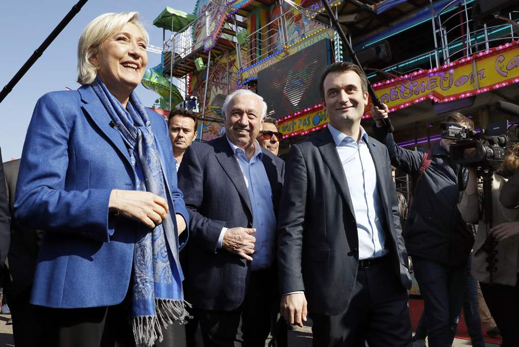 French presidential election candidate for the far-right Front National (FN) party Marine Le Pen (L) and FN Vice-President Florian Philippot (R) and the founder of the Foire du Trone, Marcel Campion, visit the fairgrounds in Paris on April 7, 2017. / AFP 