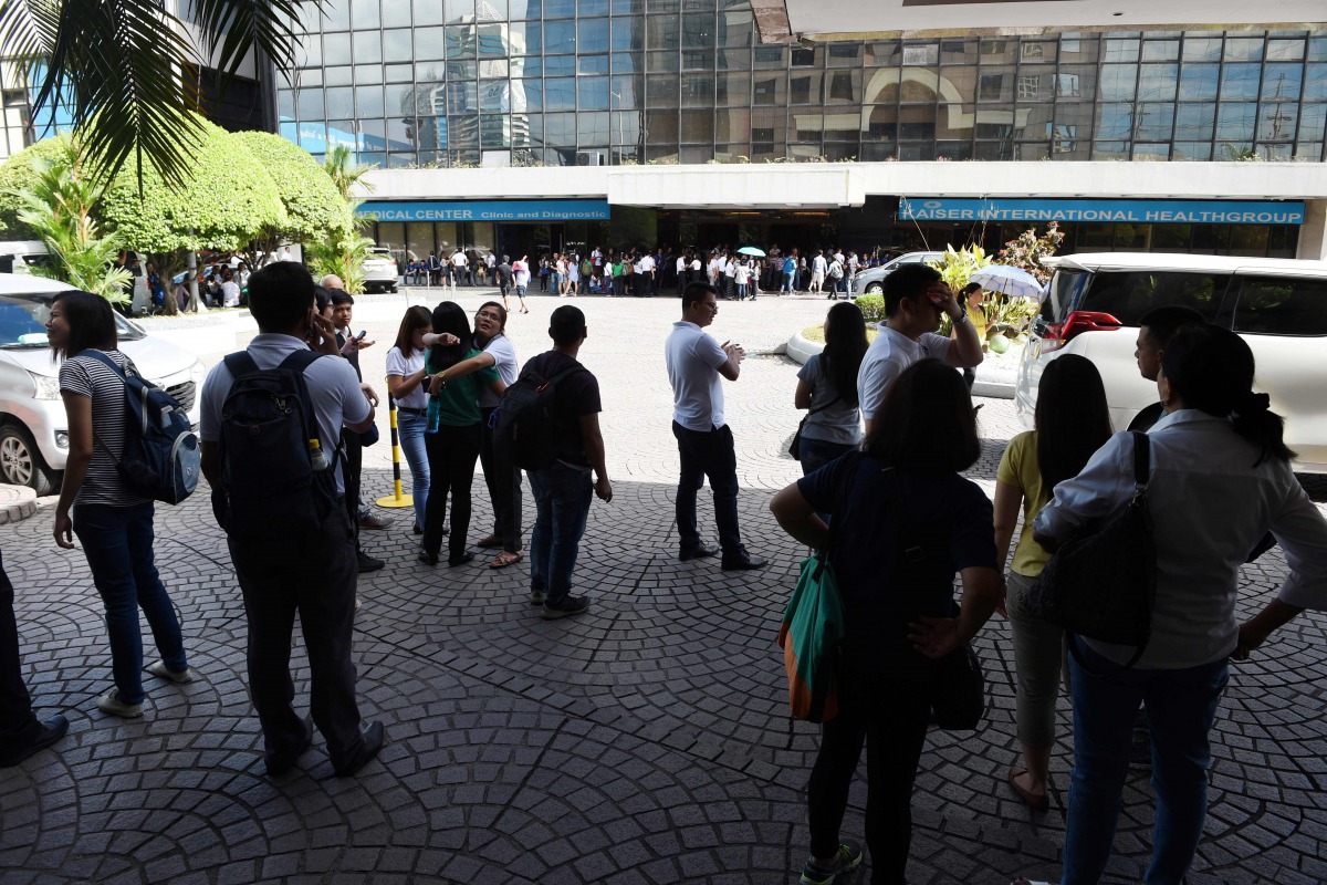 Office workers stand on the grounds of an office building in the financial district of Makati in Manila on April 8, 2017, after a 5.7 magnitude earthquake. A magnitude 5.7 earthquake rocked the Philippines on April 8, the US Geological Survey said, sendin