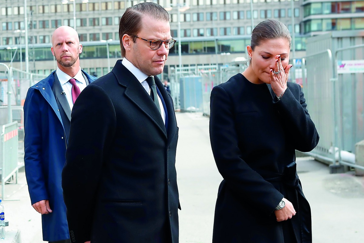 Crown Princess Victoria of Sweden and Prince Daniel react after laying down flowers at a fence near the department store Ahlens in Stockholm, yesterday. 