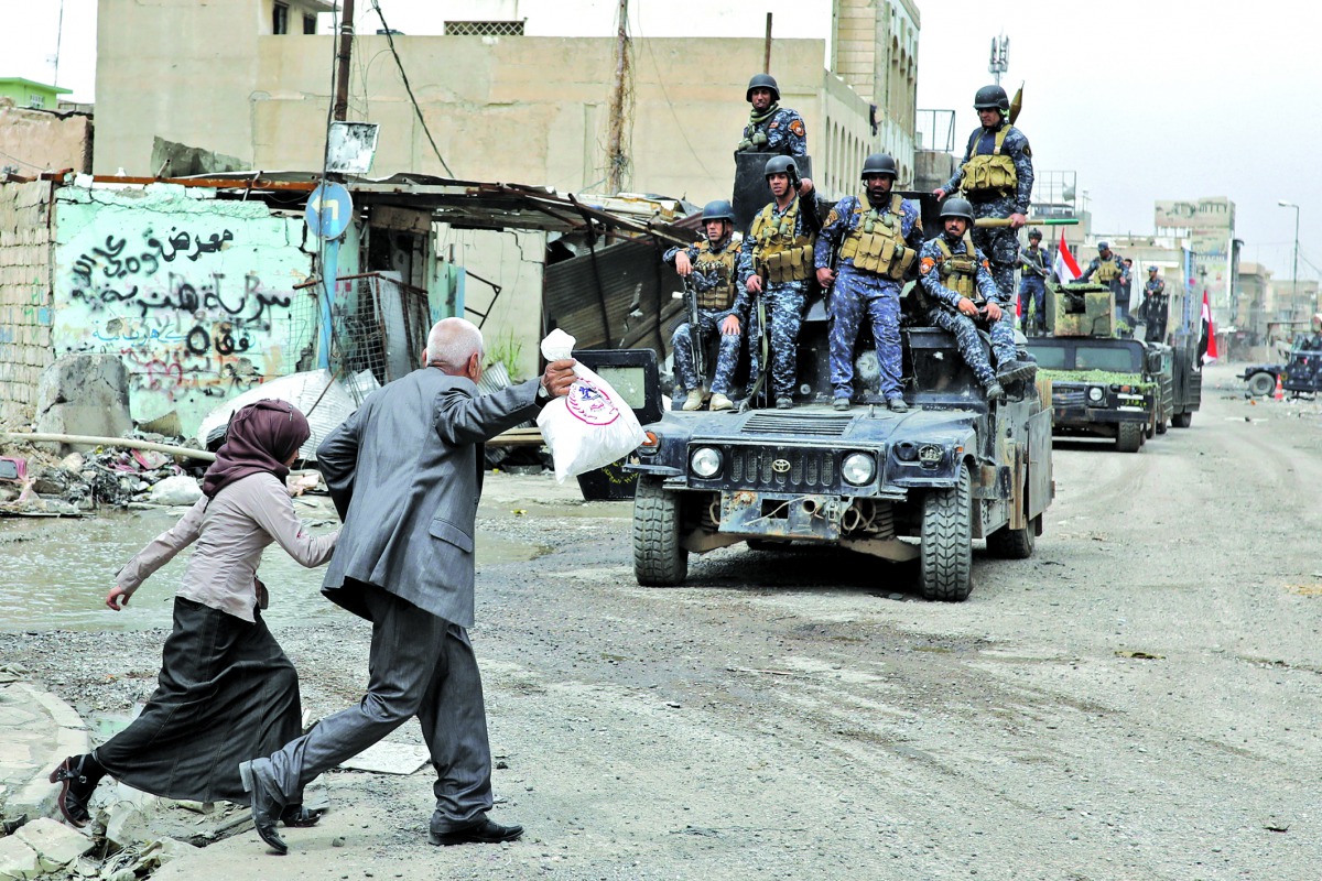 A man and a woman cheer Iraq's Federal Police members patrolling the streets of western Mosul, yesterday.