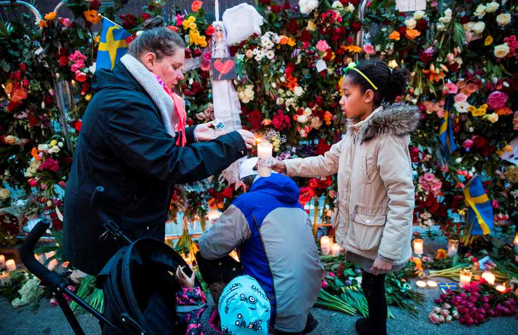 Well wishers place flowers and candles at a makeshift memorial outside a department store in Stockholm on April 8, 2017. AFP / Odd ANDERSEN
