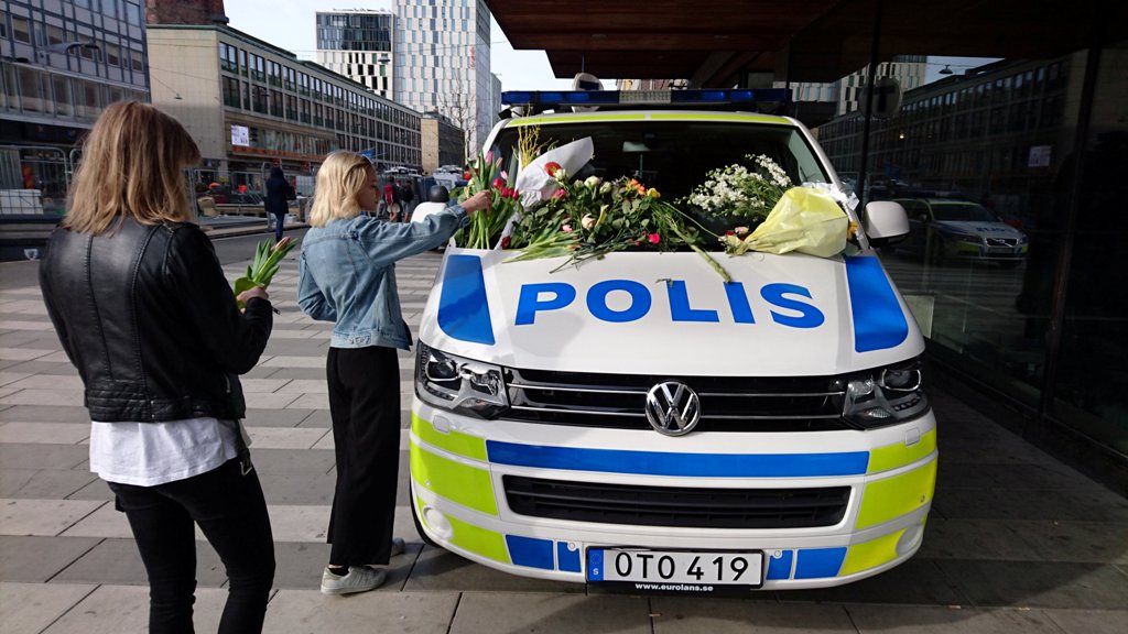 A woman puts flowers on a police vehicle near the Ahlens department store following Friday's attack in central Stockholm, Sweden, April 9, 2017. REUTERS/Philip O'Connor.