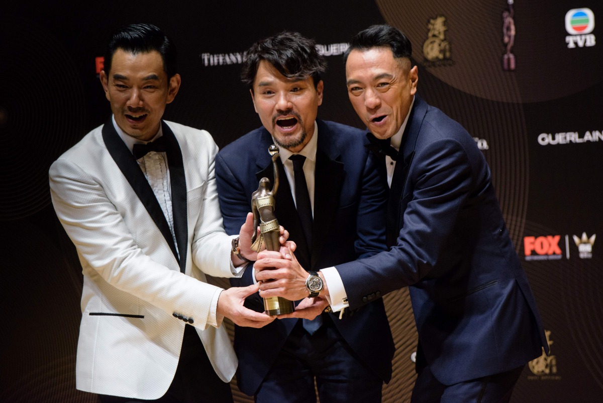 Hong Kong actor Gordon Lam (C) celebrates with fellow actors Philip Keung (R), right, and Richie Ren after Lam won the Best Actor award for his film Trivisa at the Hong Kong Film Awards ceremony in Hong Kong on April 9, 2017. AFP / Anthony Wallace