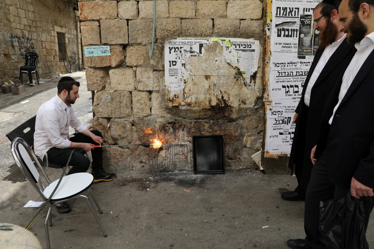 Ultra-Orthodox Jewish men sort their cooking utensils at they dip them in boiling water to remove remains of leaven in preparation for the Jewish holiday of Passover, in Jerusalem's Mea Shearim neighbourhood April 9, 2017. REUTERS/Ammar Awad