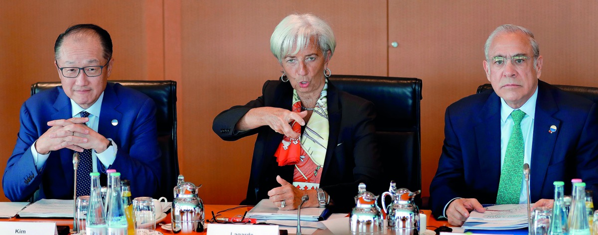 L-R) Jim Yong Kim, President of the World Bank, Christine Lagarde, Managing Director of the International Monetary Fund (IMF) and Angel Gurria, Secretary General of the Organization for Economic Cooperation and Development (OECD) talk with a member of the