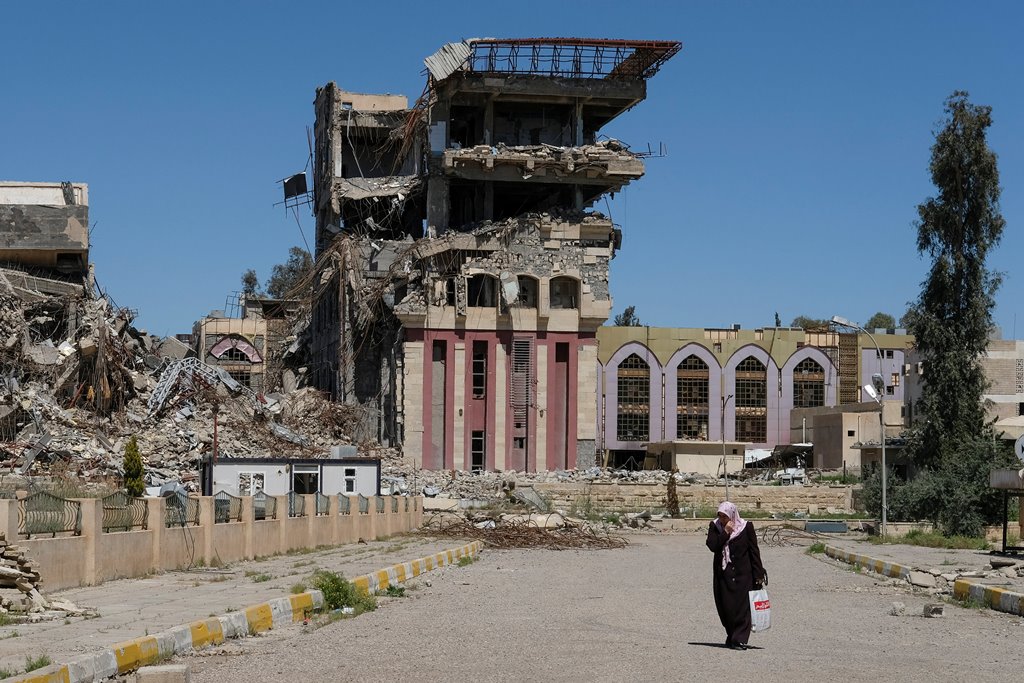 A woman walks in front of the remains of the University of Mosul, which was burned and destroyed during a battle with Islamic State militants, in Mosul, Iraq, April 10, 2017. REUTERS/Marko Djurica
