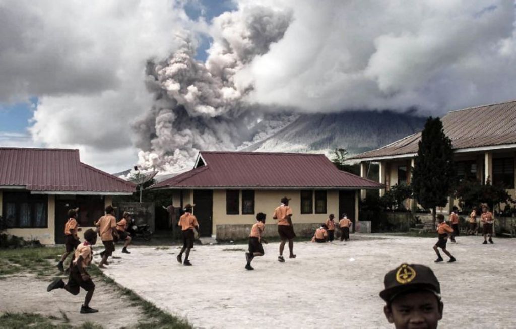 Children play at school as Indonesia's Mount Sinabung spews clouds of smoke and ash on February 10, 2017 (AFP Photo/).