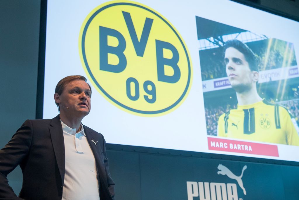 Bjoern Gulden, chairman of sports equipment maker Puma SE, stands in front of a board displaying a picture of Dortmund's injured Spanish defender Marc Bartra during his company's annual general meeting in Herzogenaurach, southern Germany, on April 12, 201