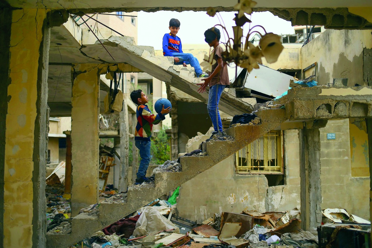 Palestinian children play amidst the ruins of a building destroyed during the 50-day war between Israel and Hamas militants during the summer of 2014 in Gaza City, on April 13, 2017. AFP / Mohammed Abed
