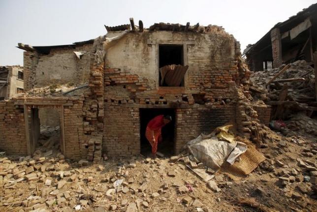 FILE PHOTO: A woman walks out from her house damaged during the 2015 earthquakes in Bhaktapur, Nepal, April 25, 2016 (Reuters / Navesh Chitrakar) 