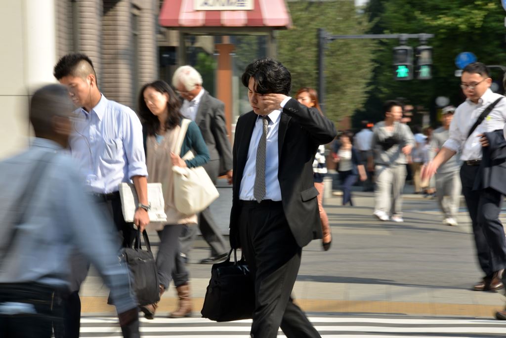 (FILES) This file photo taken on September 30, 2014 shows a Japanese businessman, called salaryman, rubbing his eyes as he heads to his office in Tokyo. AFP / YOSHIKAZU TSUNO