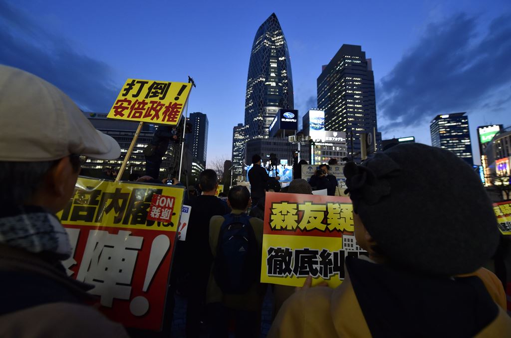 This picture taken on April 13, 2017 shows people holding various placards as they protest against Japan's conservative Prime Minister Shinzo Abe during a rally to denounce his policies and call for his resignation, outside Shinjuku Station in Tokyo. AFP 