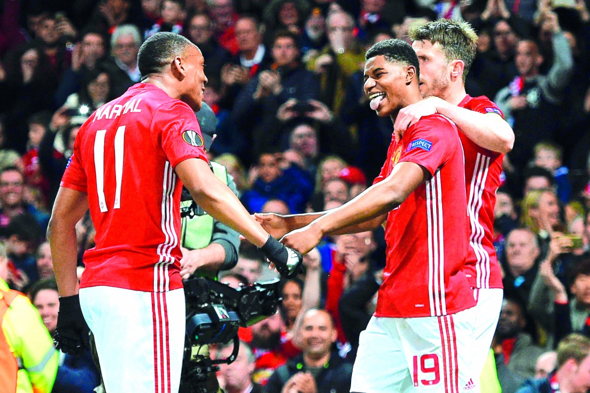 Manchester United striker Anthony Martial (left) celebrates with team-mates Marcus Rashford (centre) and Michael Carrick after their second goal during the UEFA Europa League quarter-final second leg match against Anderlecht at Old Trafford in Manchester,