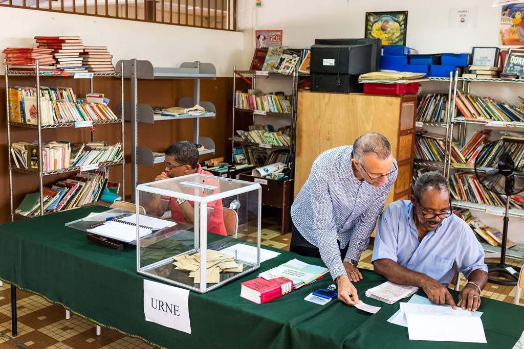 Polling station officials check on a voter list at a polling station on April 22, 2017 in Remire Montjoly, French Guiana during the first round of the French presidential election. / AFP / jody amiet
