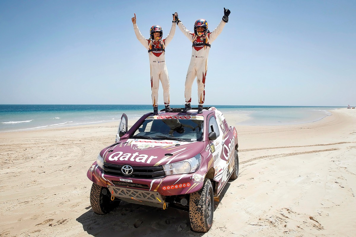 Qatari driver Nasser Saleh Al Attiyah and his French navigator Matthieu Baumel celebrate on the roof of their vehicle after winning the Qatar Cross-Country Rally at Losail yesterday.