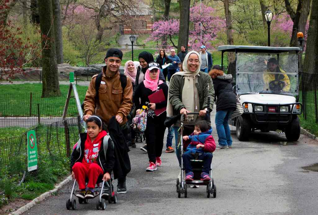 A group of mostly Syrian but some Iraqi refugee families walk through Central Park during a tour of Manhattan April 21, 2017 in New York. AFP / Don Emmert 