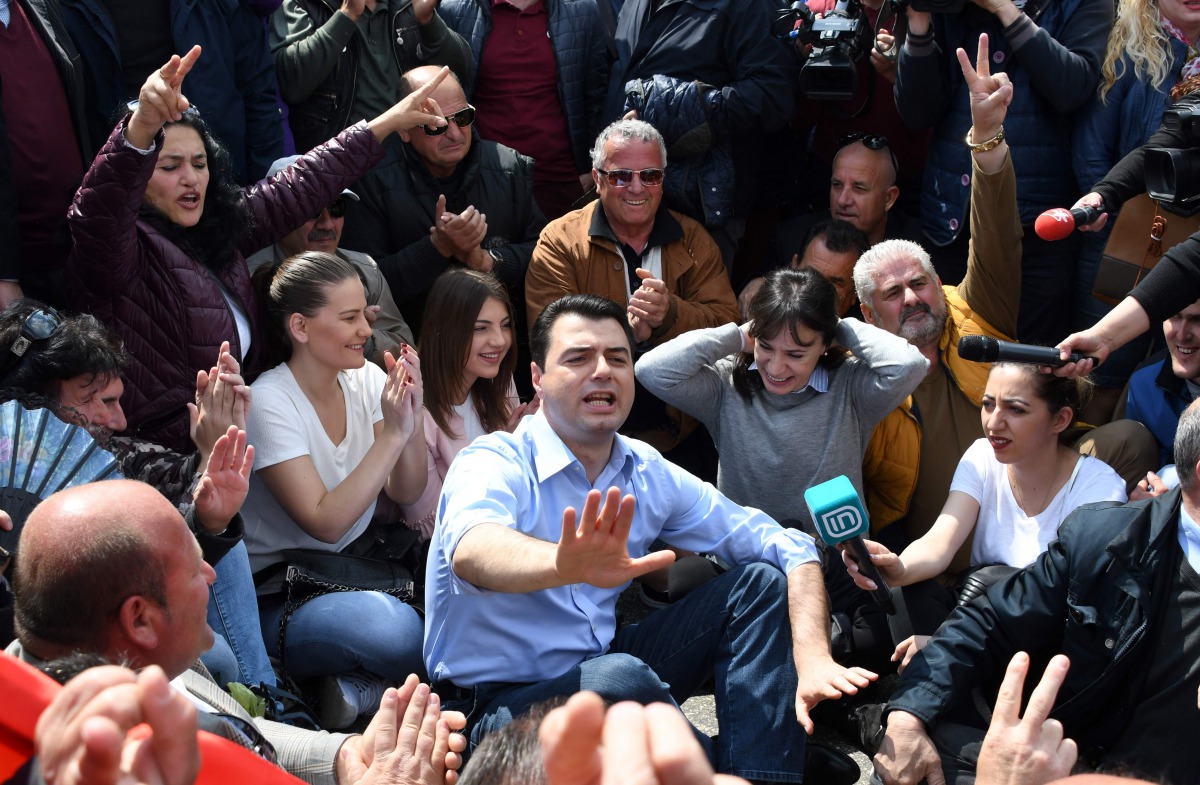 Albanian opposition leader Lulzim Basha gestures as he together with his supporters sit in the middle on a main artery of the capital to block traffic for one hour as they escalate their protest in Tirana on April 24, 2017.  AFP / Gent Shkullaku